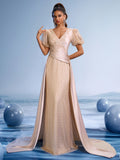 Champagne beaded mermaid evening gown with sheer sequin puff sleeves, V-neckline, and elegant satin overskirt train for weddings or galas.